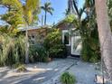 Charming home exterior featuring wood siding, lush tropical landscaping, a decorative white door, and a welcoming walkway at 4408 125Th W St, Cortez, FL 34215