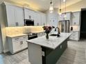 Modern kitchen showcasing white cabinetry, a large island with quartz countertops, and stainless steel appliances at 5473 Gagnon Ter, North Port, FL 34291
