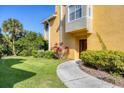 Inviting yellow two-story home featuring a well-manicured lawn and charming walkway at 5691 Bentgrass Dr # 15-101, Sarasota, FL 34235