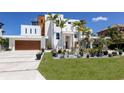 Modern home featuring a two-car garage, lush landscaping, and a spacious driveway, perfect for luxurious living at 581 Kingfisher Ln, Longboat Key, FL 34228