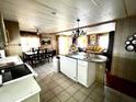 Open kitchen with white cabinetry, breakfast bar, and tile flooring, flowing into a dining and living area at 606 Cyprus Ct, Bradenton, FL 34207