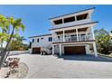 A beautiful raised beach house with a three-story design boasts multiple decks and a spacious paved driveway at 803 Gladiolus St, Anna Maria, FL 34216