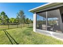Backyard featuring a screened lanai, green grass, and a black fence, perfect for outdoor enjoyment at 10806 52Nd E Ct, Parrish, FL 34219
