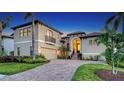 Elegant two-story home with arched entryway, brick driveway, tropical landscaping, and a two-car garage at 12614 Safe Harbour Dr, Cortez, FL 34215