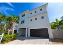 Modern two story home with brick driveway, dark garage doors, and mature tropical landscaping at 205 17Th N St, Bradenton Beach, FL 34217