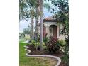 Exterior view showcasing the landscaped front yard with palm trees, flowers and decorative concrete edging at 213 Babbling Brook Run, Bradenton, FL 34212