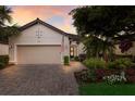 Home boasts manicured landscaping, a brick walkway, and an attached two-car garage, set against a beautiful sky at 2397 Vaccaro Dr, Sarasota, FL 34231