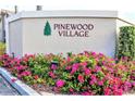 Attractive Pinewood Village community sign surrounded by lush, colorful flowers at 2763 Woodgate Ln # 108, Sarasota, FL 34231