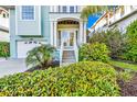 Inviting home entrance featuring double doors, a staircase, and vibrant landscaping with colorful foliage at 426 Magnolia Ave, Anna Maria, FL 34216