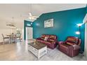 Cozy living room featuring a comfortable leather sofa, blue accent wall, tile floors, and adjacent dining area at 6330 Green Oak Cir, Bradenton, FL 34203