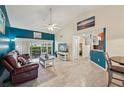Bright living room with blue accent wall, tile floors, ceiling fan, and sliding glass doors to the lanai at 6330 Green Oak Cir, Bradenton, FL 34203