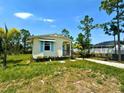 Quaint home with blue shutters nestled on a grassy lot with lush trees and a glimpse of the pool area at 8297 Strasse Blvd, Punta Gorda, FL 33982