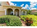 Arched entryway with colorful landscaping and white columns, highlighting the home's inviting curb appeal at 12838 Daisy Pl, Bradenton, FL 34212