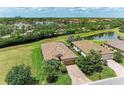 An aerial view of the home, revealing the terracotta roof, brick driveway, and adjacent pond at 157 Wandering Wetlands Cir, Bradenton, FL 34212