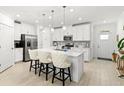 Bright kitchen features a large island with seating, stainless steel appliances, and ample white cabinetry at 17576 Holly Well Ave, Wimauma, FL 33598