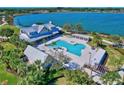 Aerial view of community pool, clubhouse, and lake with lounge chairs and palm trees at 17732 Wayside Bnd, Punta Gorda, FL 33982