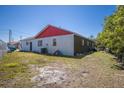 The back of the house with partial paint in red and white, with a yard in need of landscaping at 1821 16Th E Ave, Bradenton, FL 34208
