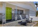 Charming front porch with seating, decorative columns, and a vibrant green front door at 2647 Britannia Rd, Sarasota, FL 34231