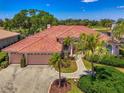 Beautiful single-story home boasts a terracotta tile roof, two-car garage, and lush landscaping at 407 Fieldstone Dr, Venice, FL 34292