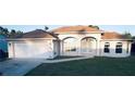 Front exterior view of house featuring a two-car garage, well-manicured lawn, and a beautiful front entryway at 4456 Callaway St, Port Charlotte, FL 33981