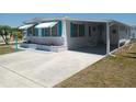 Bright home featuring awnings, a brick planter and a long concrete driveway and carport at 4920 Boca Raton Ave, Sarasota, FL 34234