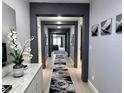 Elegant hallway with gray walls, modern decor, and an artistic rug leading to a brightly lit living area at 4970 Oyster Pearl St, Lakewood Ranch, FL 34211