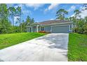 Beautiful one-story home with a long driveway and an attached two-car garage surrounded by lush greenery at 5672 Jonesboro Ave, North Port, FL 34288