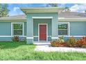 Charming home exterior featuring a inviting entryway and colorful landscaping and two large windows at 5672 Jonesboro Ave, North Port, FL 34288