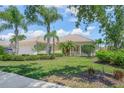 Charming one-story home featuring a well-manicured lawn, lush landscaping, and a welcoming entrance at 5821 Valente Pl, Sarasota, FL 34238