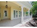 Covered porch with white columns, neutral tiling, glass doors, and an elegant lantern at 5821 Valente Pl, Sarasota, FL 34238