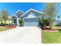 This home features a blue exterior, manicured landscaping, and a two-car garage at 6106 New Paris Way, Ellenton, FL 34222