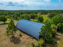 Large storage building with a metal roof surrounded by lush greenery on a sprawling property at 6321 279Th E St, Myakka City, FL 34251