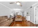 Cozy living room featuring wood floors, a ceiling fan, and an open layout leading to the dining area and kitchen at 7203 Curtiss Ave # 3D, Sarasota, FL 34231