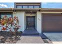 Inviting front entrance with a well-kept lawn, beautiful landscaping, and a dark two-door garage at 75 Inlets Blvd # 75, Nokomis, FL 34275