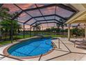 A screened-in pool and spa overlook a tranquil lake, surrounded by lush tropical landscaping at 7574 Camden Harbour Dr, Bradenton, FL 34212