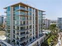 Modern condominium exterior featuring multiple balconies and a shared swimming pool at 111 Golden Gate Pt # 802Ph, Sarasota, FL 34236