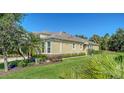 Lovely home exterior featuring manicured lawn, shrubbery and palm trees around the foundation at 11847 Meadowgate Pl, Lakewood Ranch, FL 34211