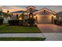 Well-lit house at dusk with manicured lawn and inviting curb appeal at 12565 Ryegrass Loop, Parrish, FL 34219