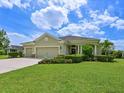 Attractive single-story home featuring a lush green lawn, a three-car garage, and colorful flowering shrubbery at 16711 Rivers Reach Blvd, Parrish, FL 34219