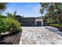 Modern home with a large paver driveway leading to a two-car garage surrounded by lush landscaping at 2632 Hawthorne St, Sarasota, FL 34239