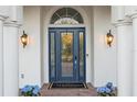 Elegant front entryway with a leaded glass door, columns, sconces, and planters with blue hydrangeas at 3415 162Nd E Ave, Parrish, FL 34219