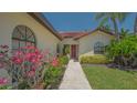 Close-up view of home entrance showcasing mature, verdant landscaping and tiled roof at 4691 Las Brisas Ln, Sarasota, FL 34238