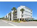 Low angle of the white beach condos with palm trees, blue skies, and an inviting coastal allure at 4800 Gulf Of Mexico Dr # 205, Longboat Key, FL 34228