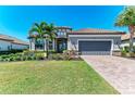 A charming home boasts a well-manicured lawn, lush landscaping, and a brick driveway leading to a two-car garage at 4908 Tivoli Run, Bradenton, FL 34211