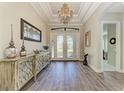 Inviting foyer featuring a decorative chandelier, tray ceiling, wooden floors, and elegant double doors at 4908 Tivoli Run, Bradenton, FL 34211