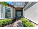 Elegant front entrance with glass double doors, stone accents, and lush landscaping at 4908 Tivoli Run, Bradenton, FL 34211