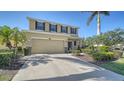 Two-story home with tan exterior, dark shutters, two-car garage, and landscaped front yard at 5403 Mang Pl, Sarasota, FL 34238