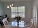 Dining area with glass table, white chairs, modern lighting, and large window at 5741 Soldier Cir # 202, Sarasota, FL 34233