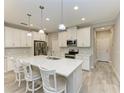 Bright kitchen featuring an island with a quartz countertop, stainless steel appliances, and white cabinets at 5957 Amberly Dr, Bradenton, FL 34208