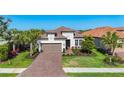 Beautiful single-Gathering home with a tile roof, attached garage, brick driveway, and well-manicured lawn at 6290 Mesa Gln, Bradenton, FL 34203